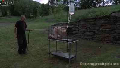 Juliette March is outside in the cage getting sprayed with cold water